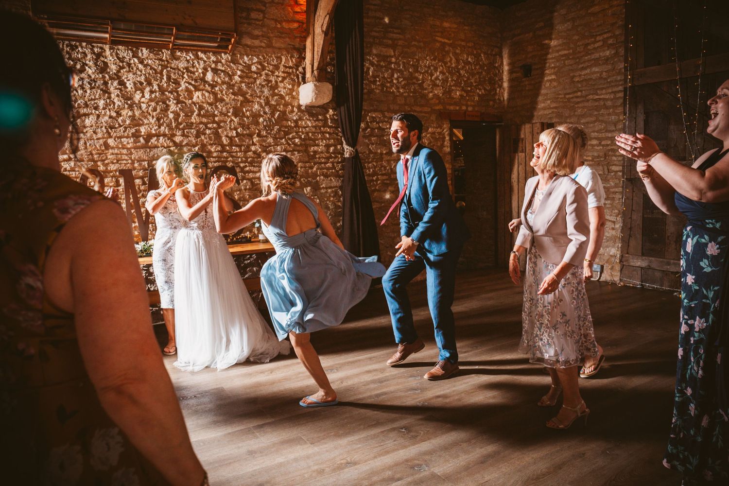 Wedding celebration with dancing guests in a rustic brick-walled venue.