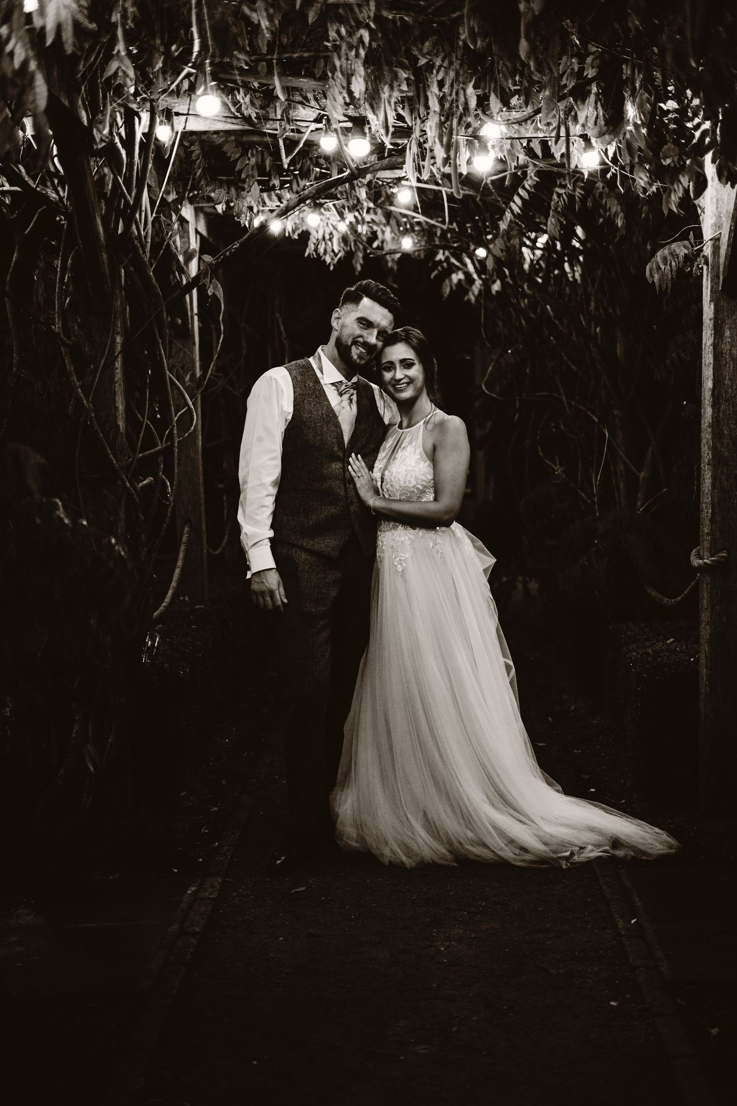 Black and white romantic wedding portrait with couple in garden at night.