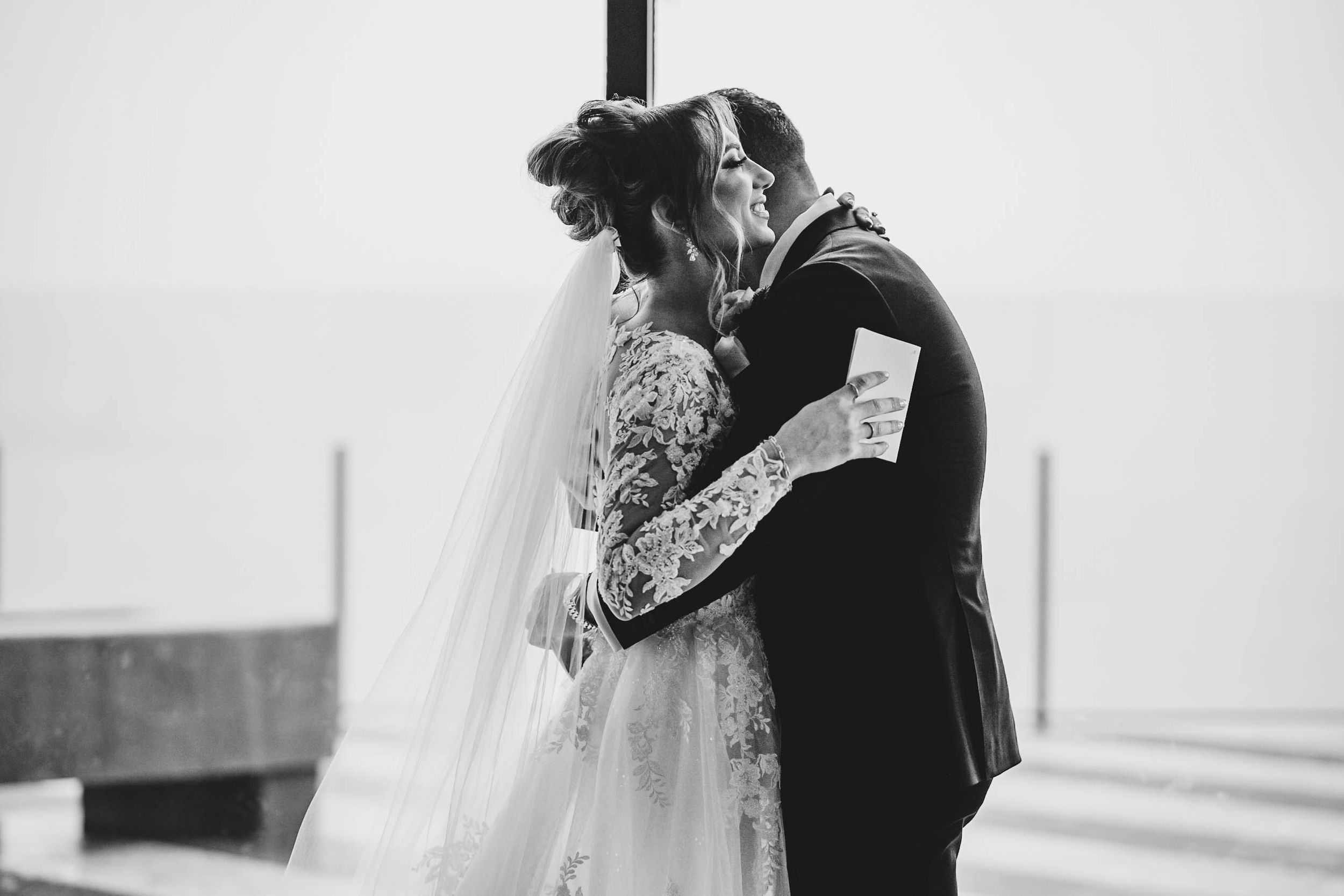 Emotional wedding first look captured in black and white as couple stands together.