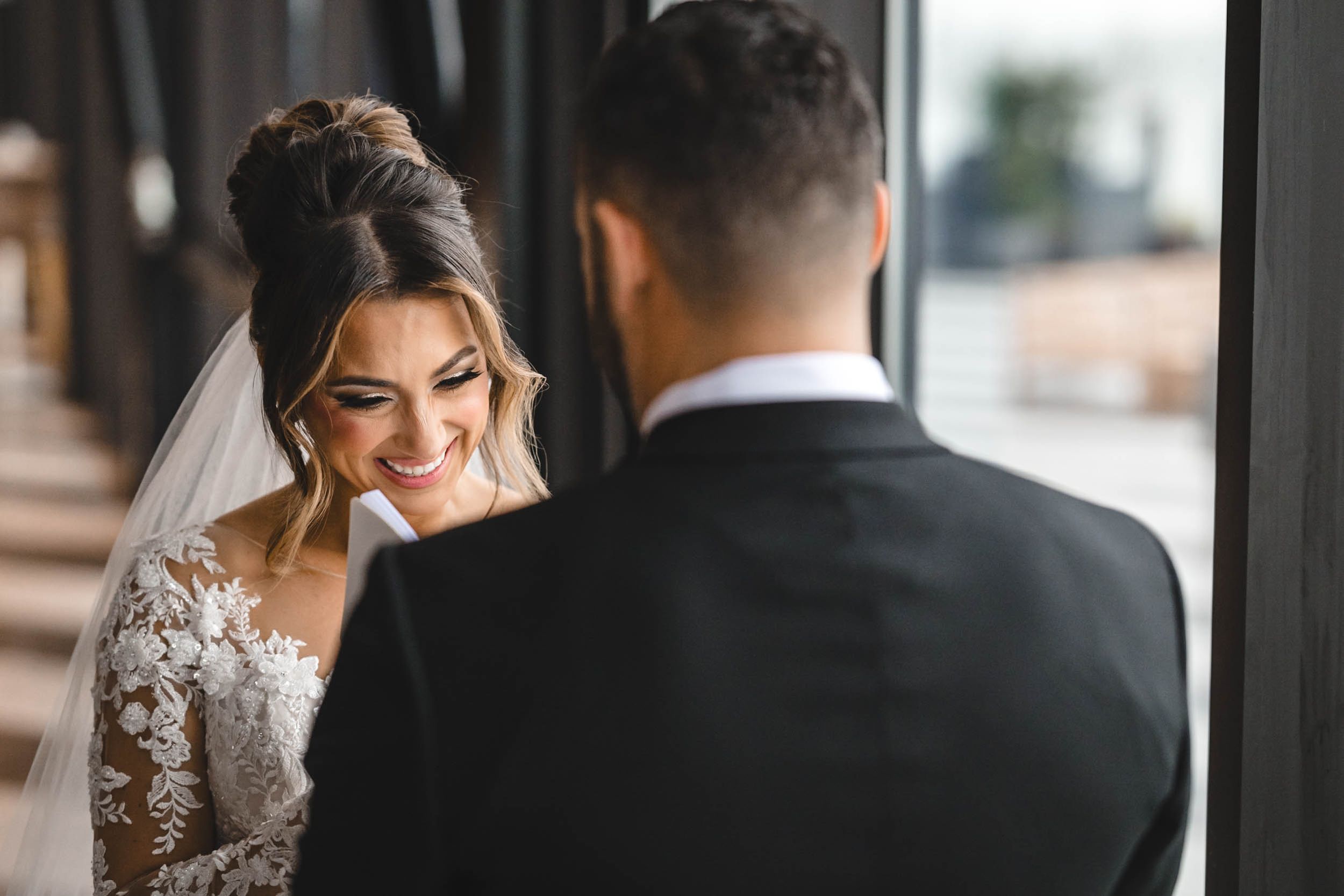Romantic first look between bride in lace gown and groom in classic tuxedo.