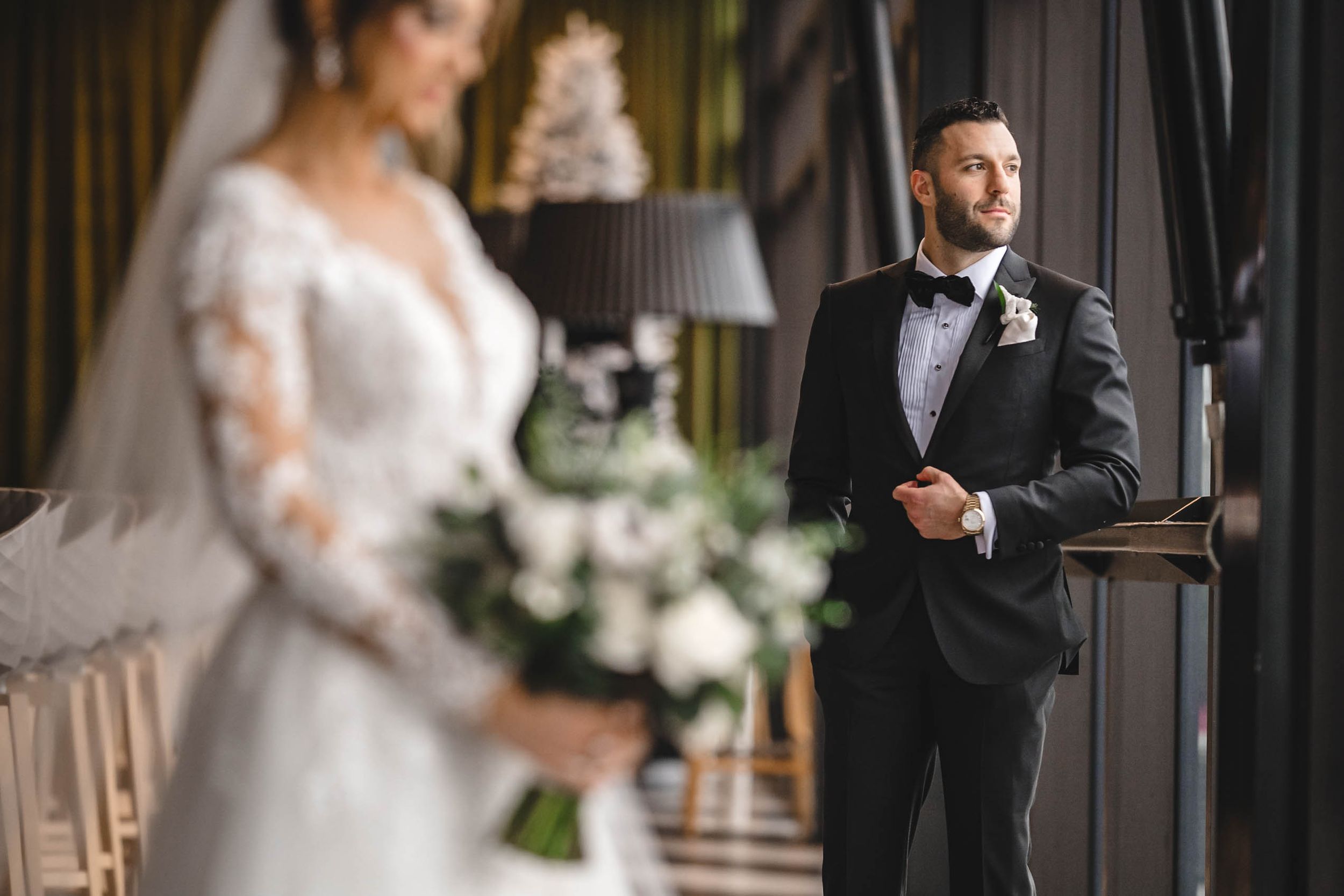 Bride in flowing white gown and groom share private moment during wedding first look.