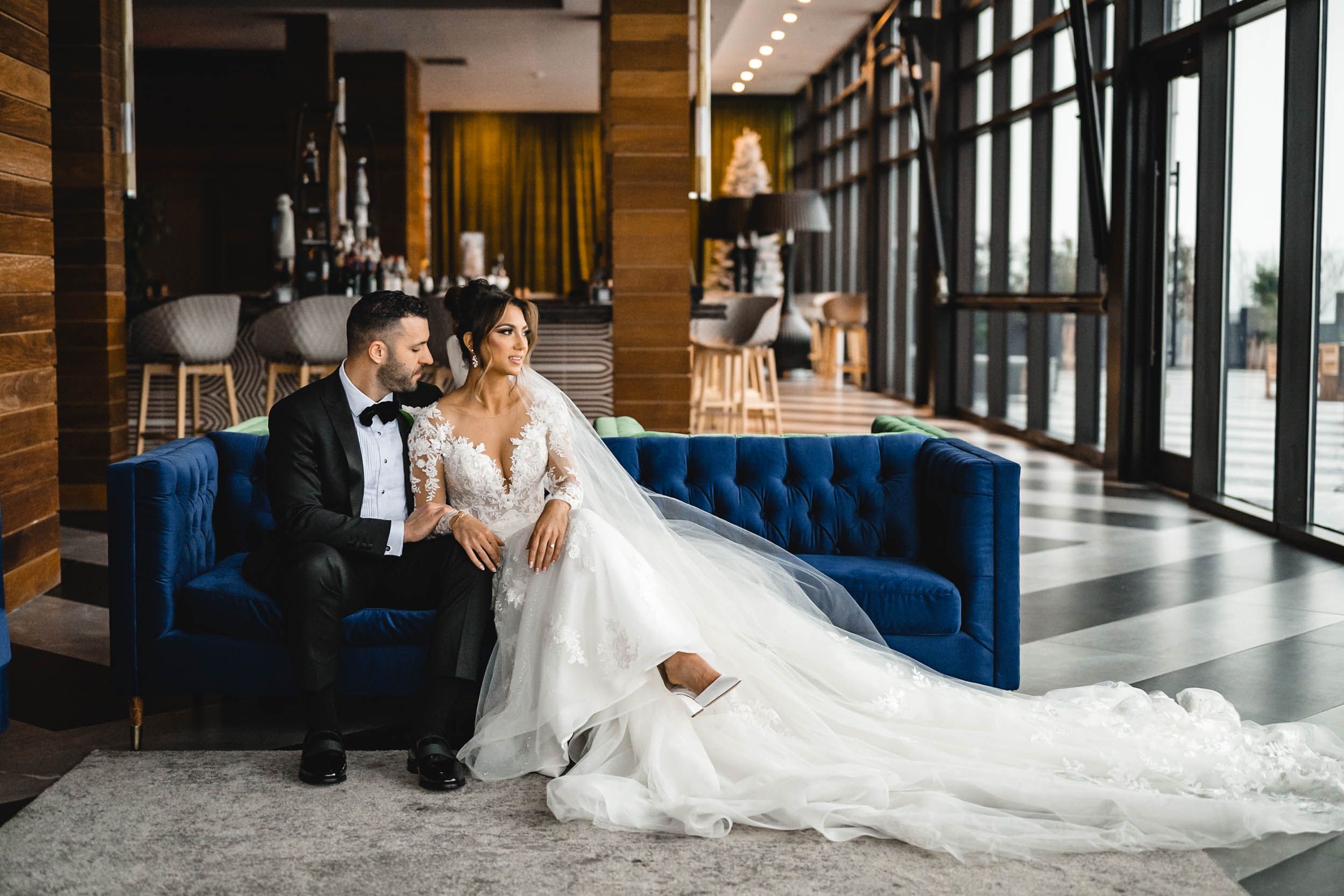Wedding couple shares intimate moment in modern venue with large windows and wooden accents.
