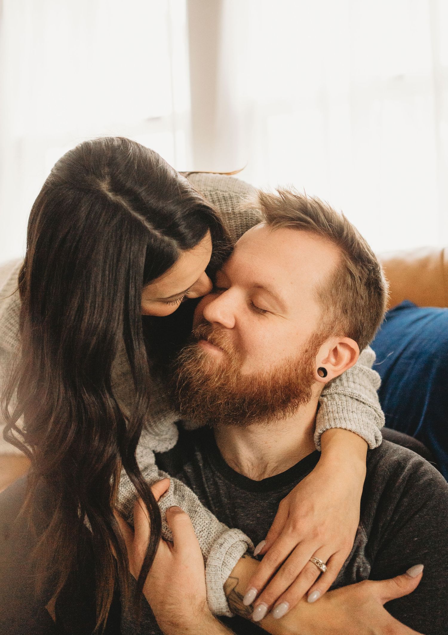 An intimate moment captured between a couple showing affection on a leather sofa.