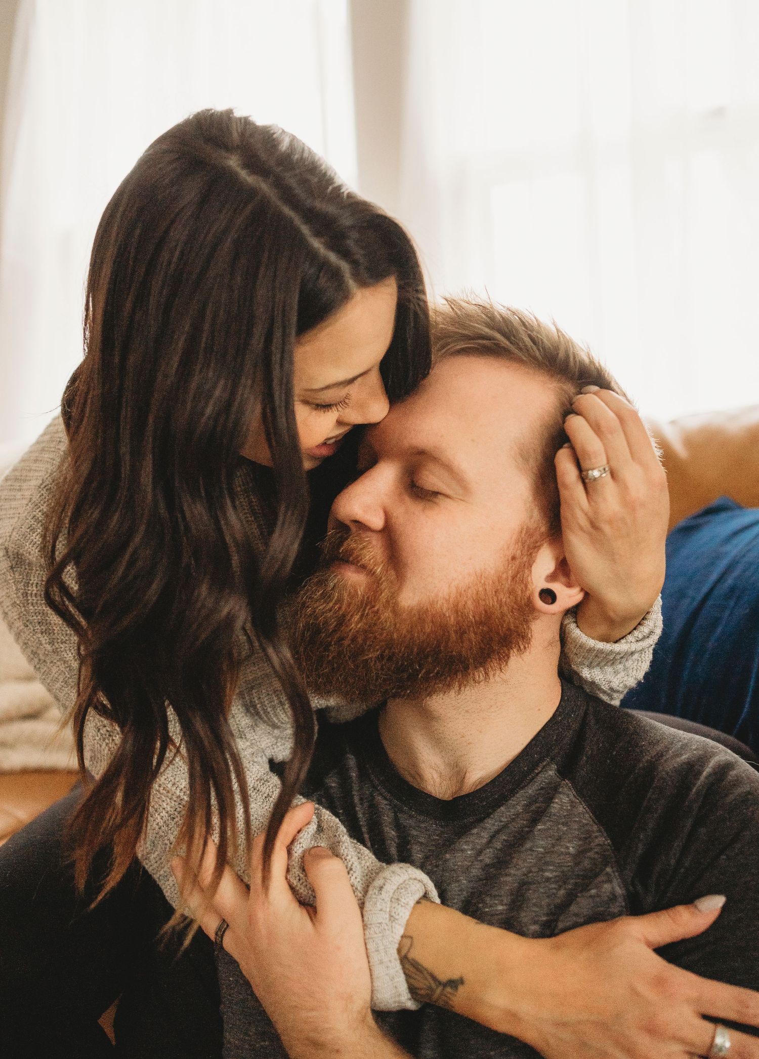 A tender moment between a couple as they share an intimate embrace on their couch.