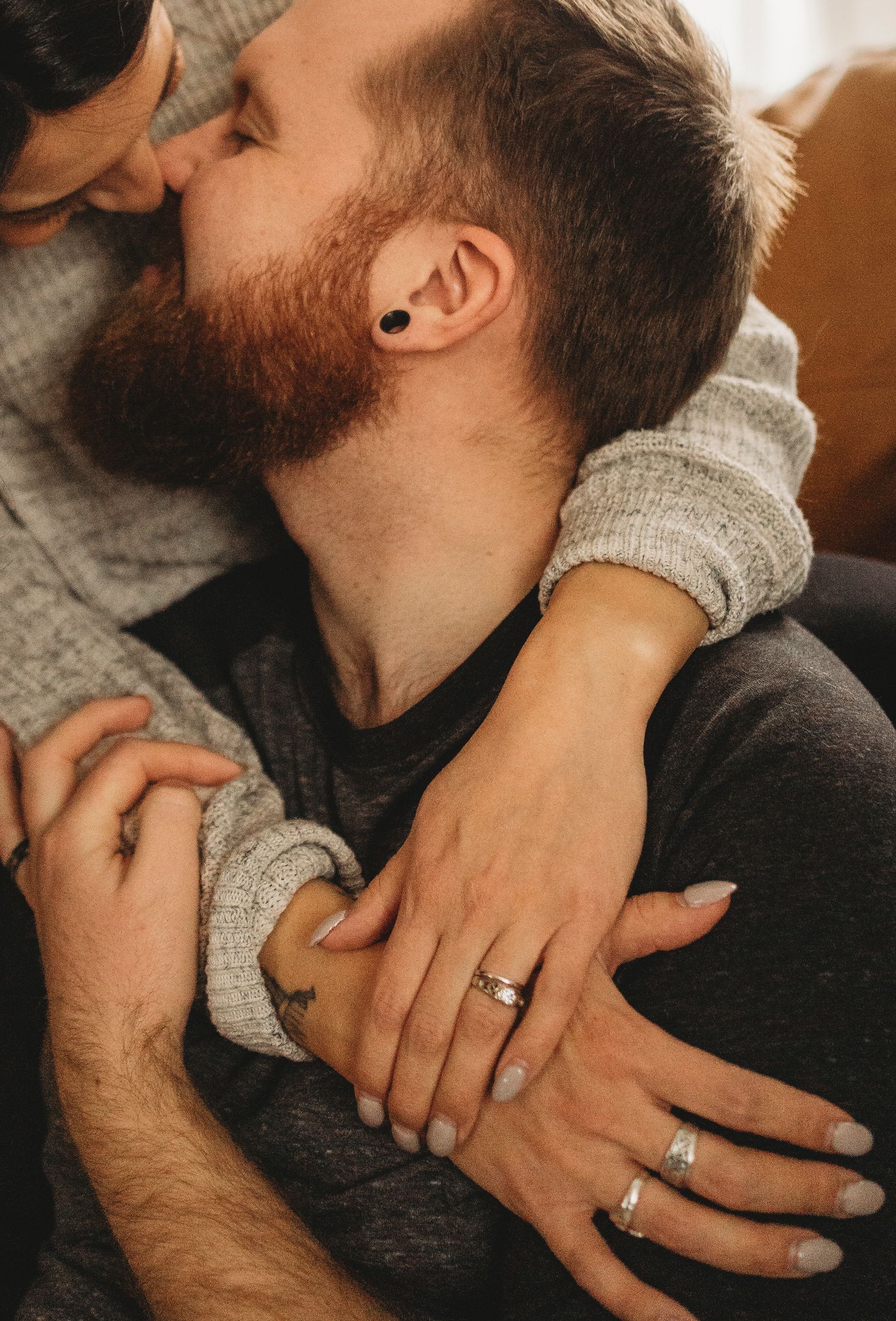 A close-up shot captures hands with wedding rings during an intimate moment.
