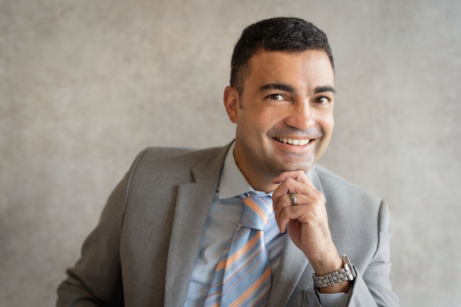 A professionally dressed man smiles to the camera for a headshot session