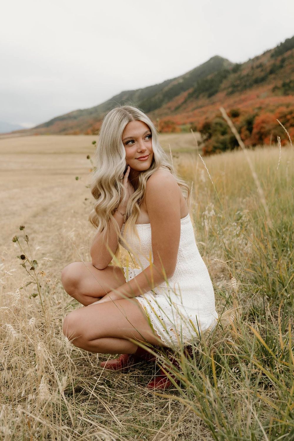 Elegant outdoor portrait session featuring a white dress amid autumn mountain scenery.
