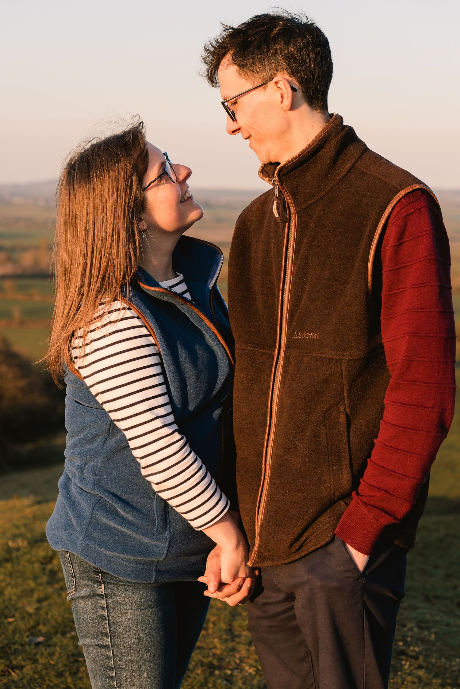 A young couple looking at each other, holding hands and smiling.