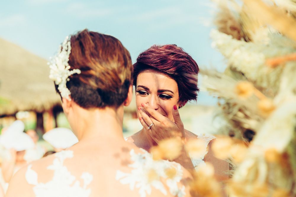 Emotional outdoor wedding scene with two people in white lace dresses sharing a joyful moment.