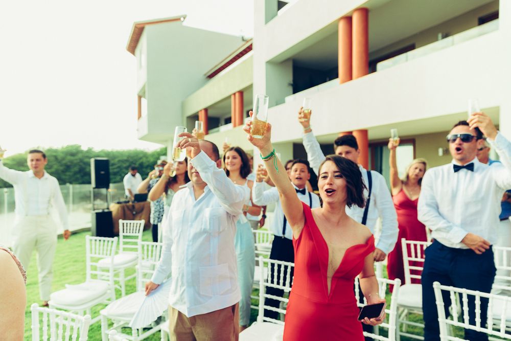 Wedding guests and wedding party standing and cheering during an outdoor celebration.