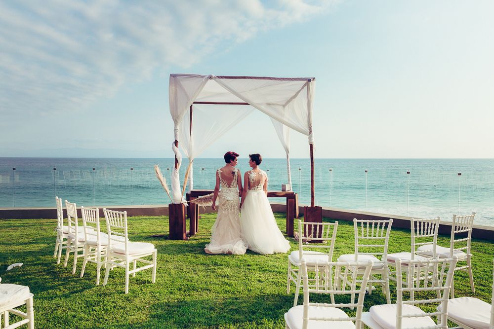 Wedding ceremony setup on oceanfront lawn with white canopy and rows of chairs facing the sea.