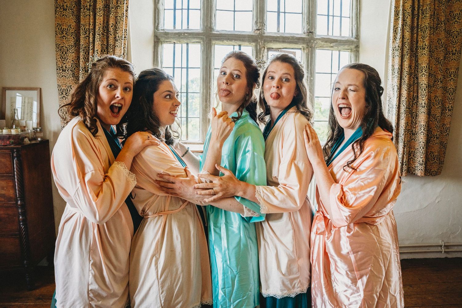 Wedding party in mint green and peach dresses posing together.