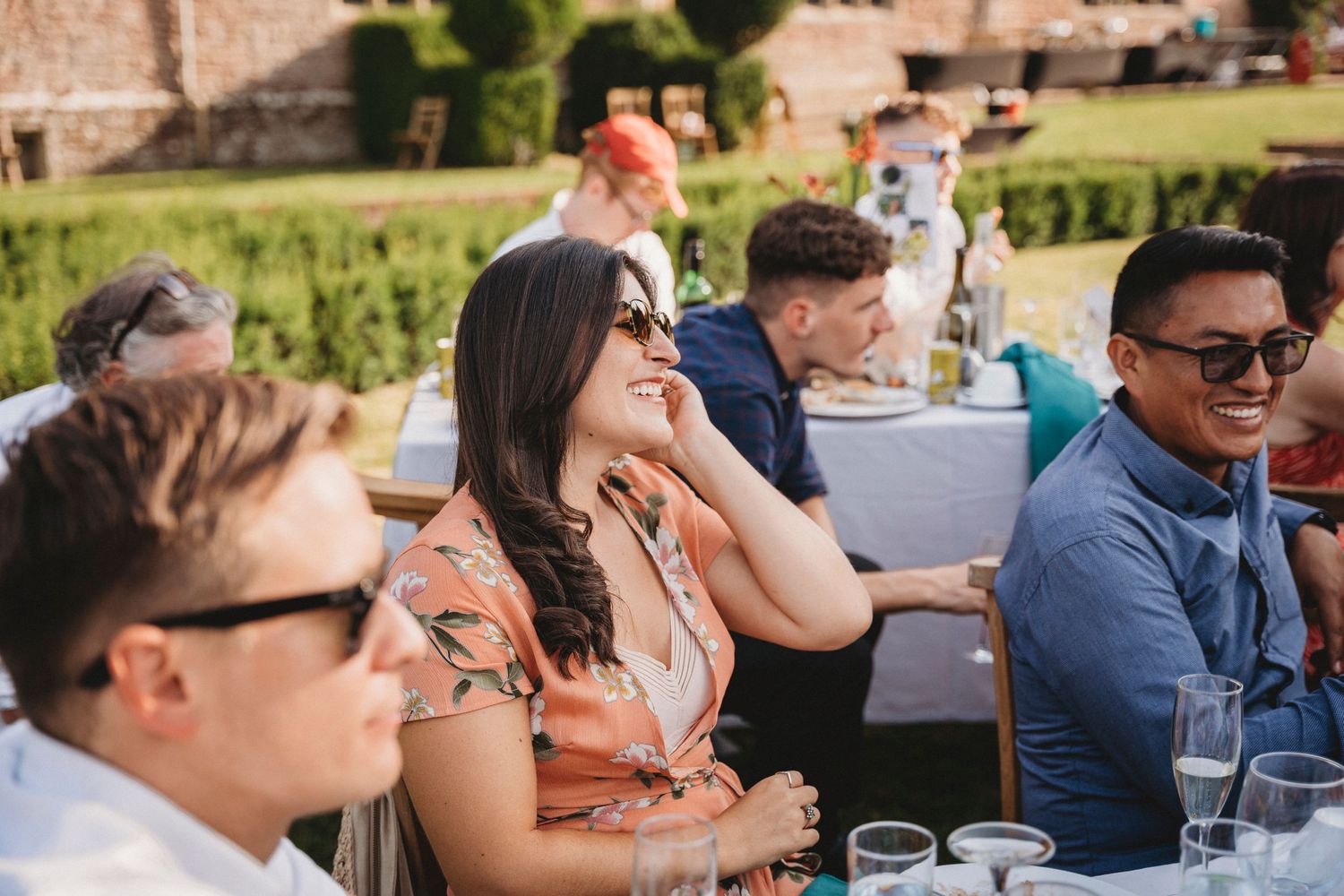 Candid moments of guests laughing and socializing at an outdoor wedding reception.