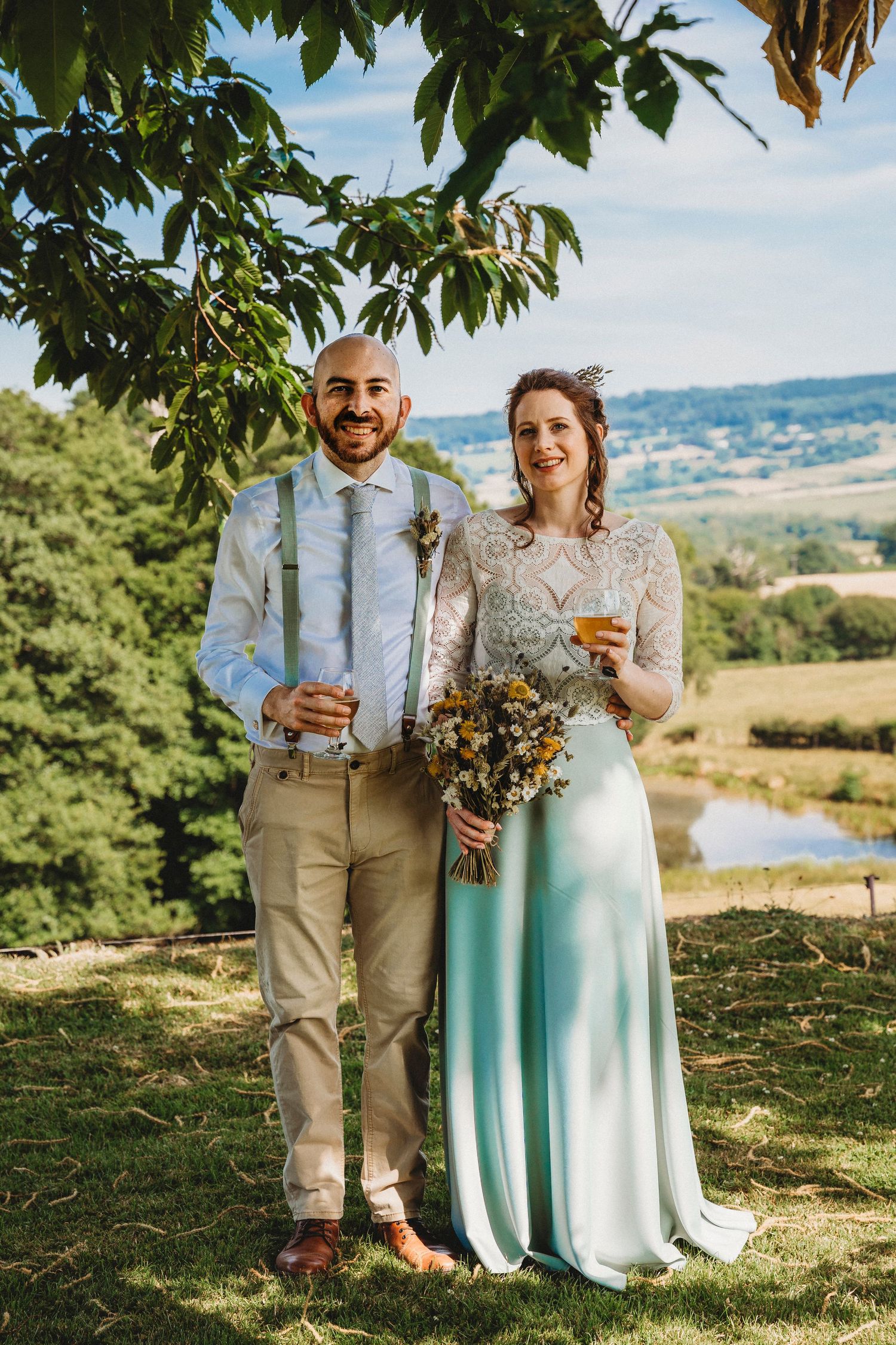Couple enjoys drinks together on hillside overlooking scenic countryside view.