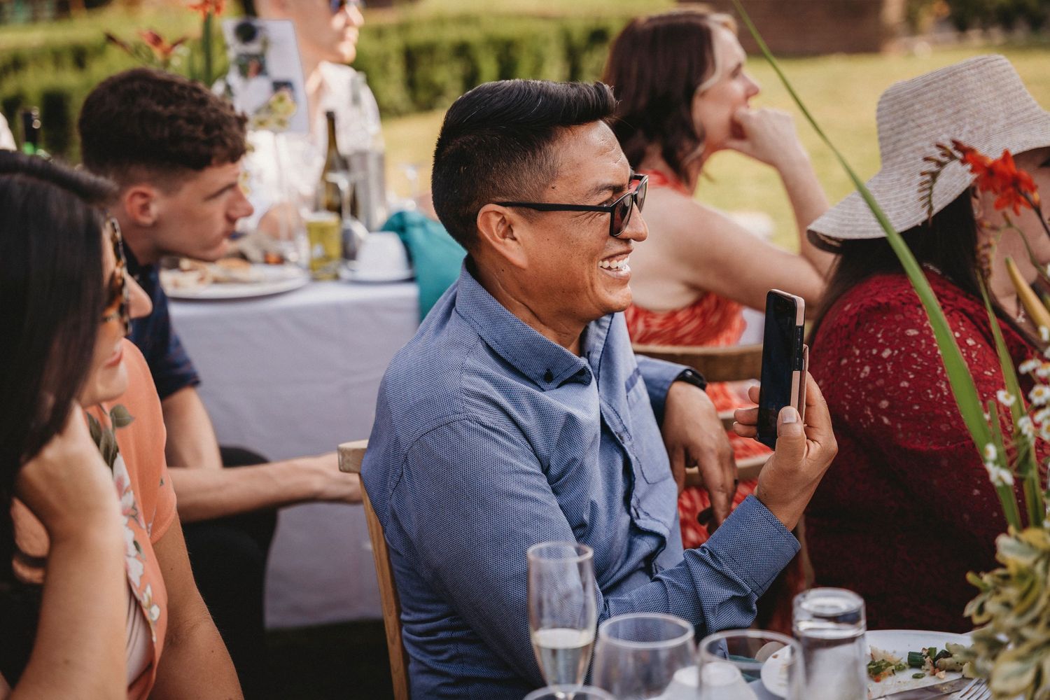 Wedding reception guests seated at long tables sharing conversation and laughter.