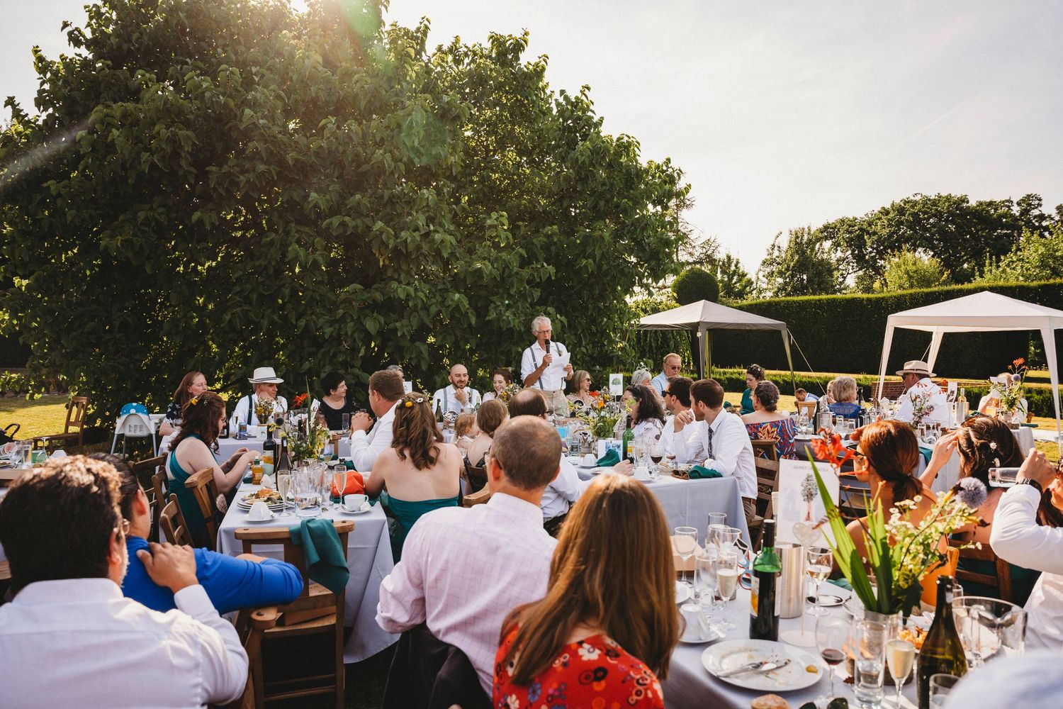 Long tables set for outdoor wedding reception under evening sky.
