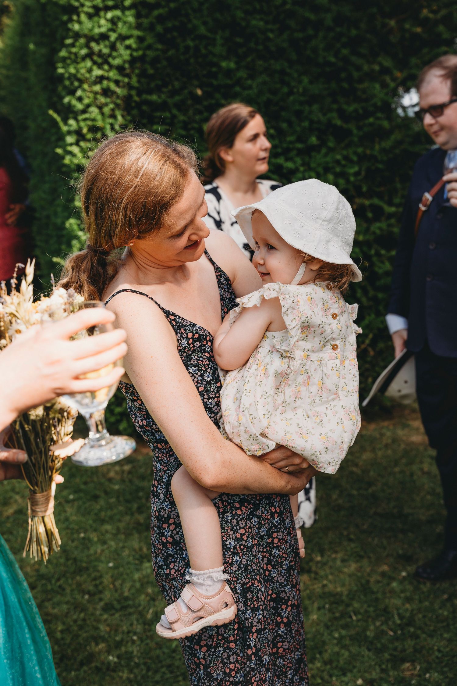 Guests share joyful embraces during outdoor garden wedding reception.