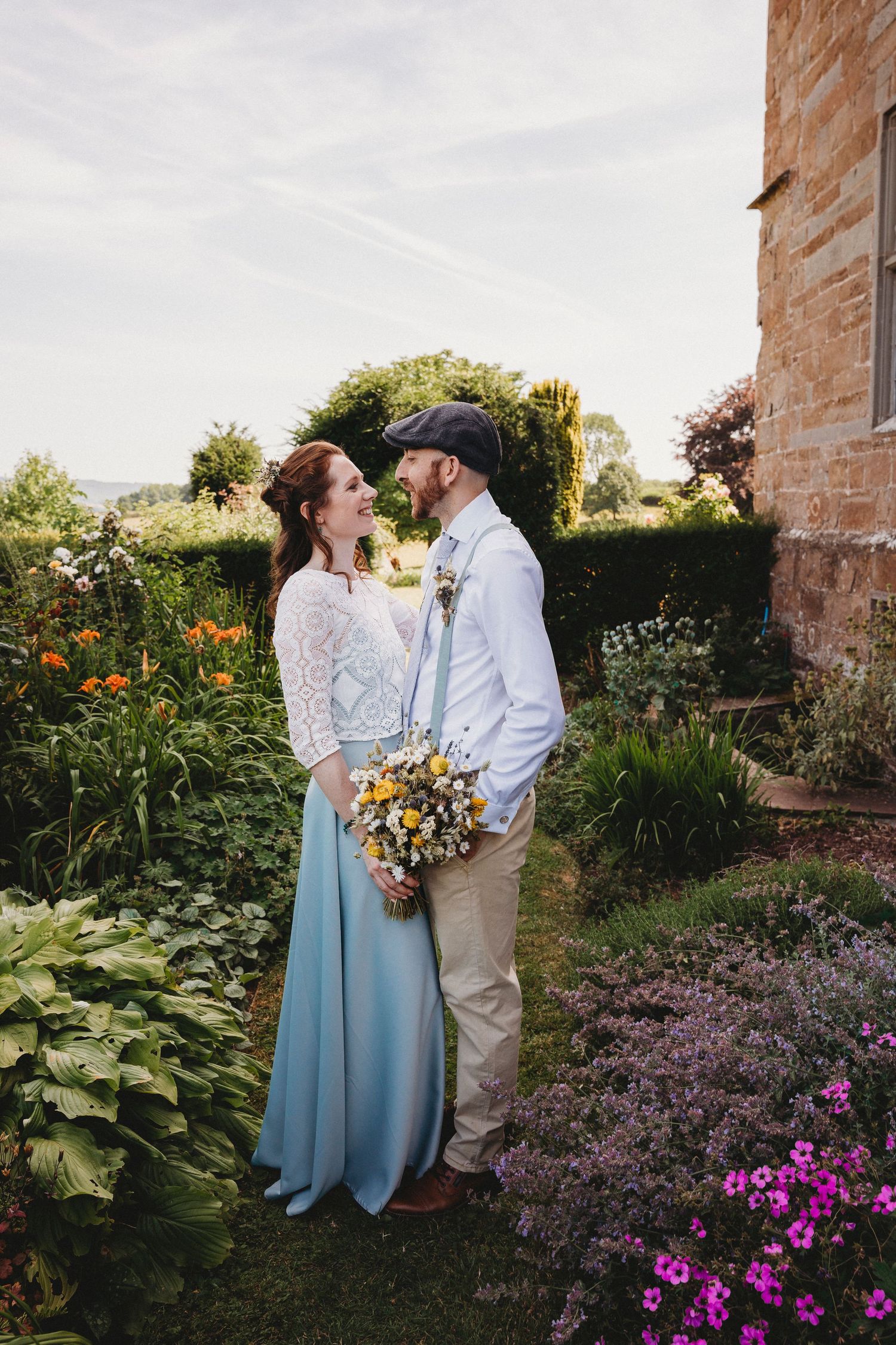 Romantic garden portraits with blooming flowers and historic stone building backdrop.
