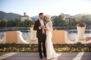 Elegant couple sharing a romantic moment on a terrace overlooking mountains at sunset.
