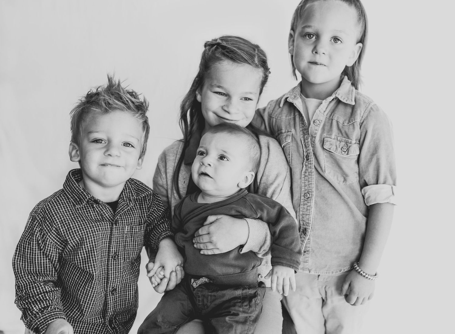 Black and white portrait of four siblings standing together.