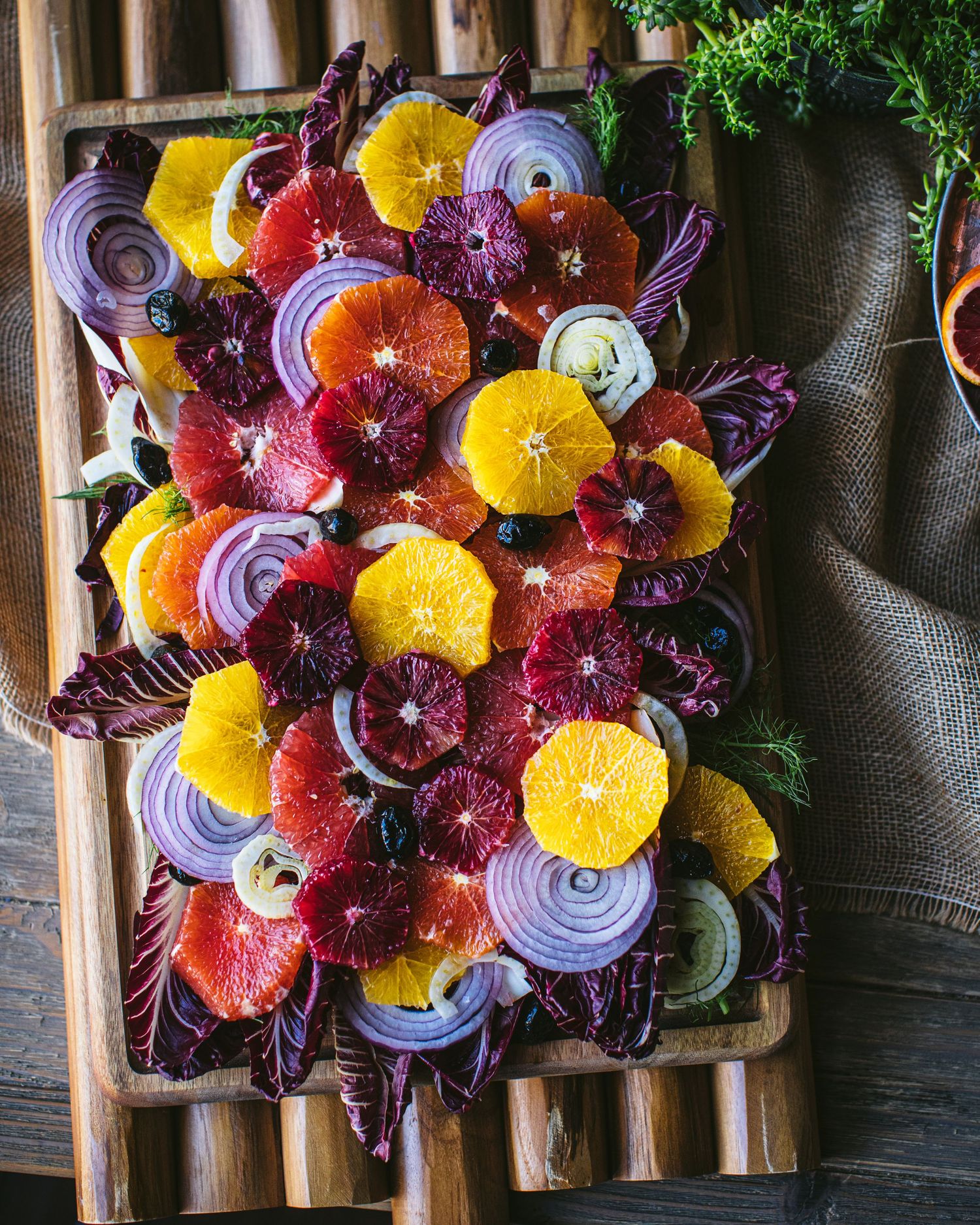 Top-down view of a citrus and radicchio salad with blood oranges and onions on a wooden board.