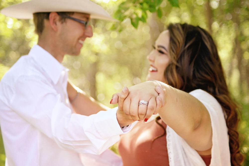 Couple in white and red outfits sharing romantic moments in sunlit outdoor setting.