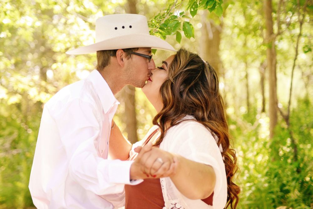 Romantic couple sharing tender moments in sunlit natural setting.