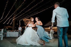 Wedding party members share a fun moment on the dance floor under string lights.