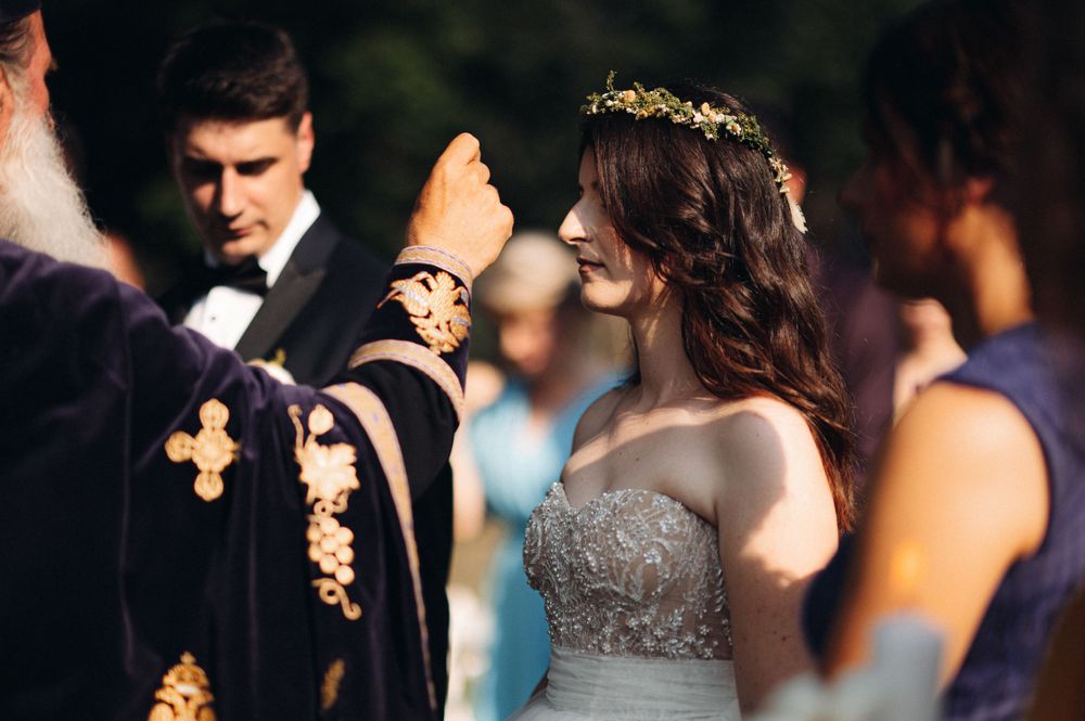 An Orthodox priest performs a traditional wedding ceremony outdoors.