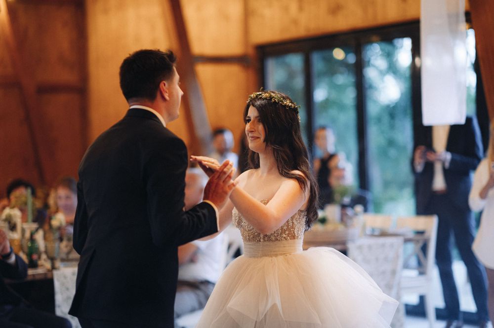 Couple shares romantic dance moment in rustic barn venue with elegant decorations.