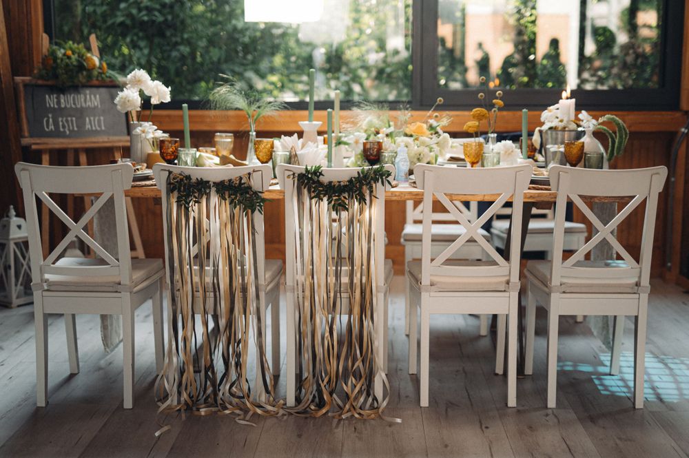 An elegant wedding reception table with white chairs and flowing ribbon decorations.