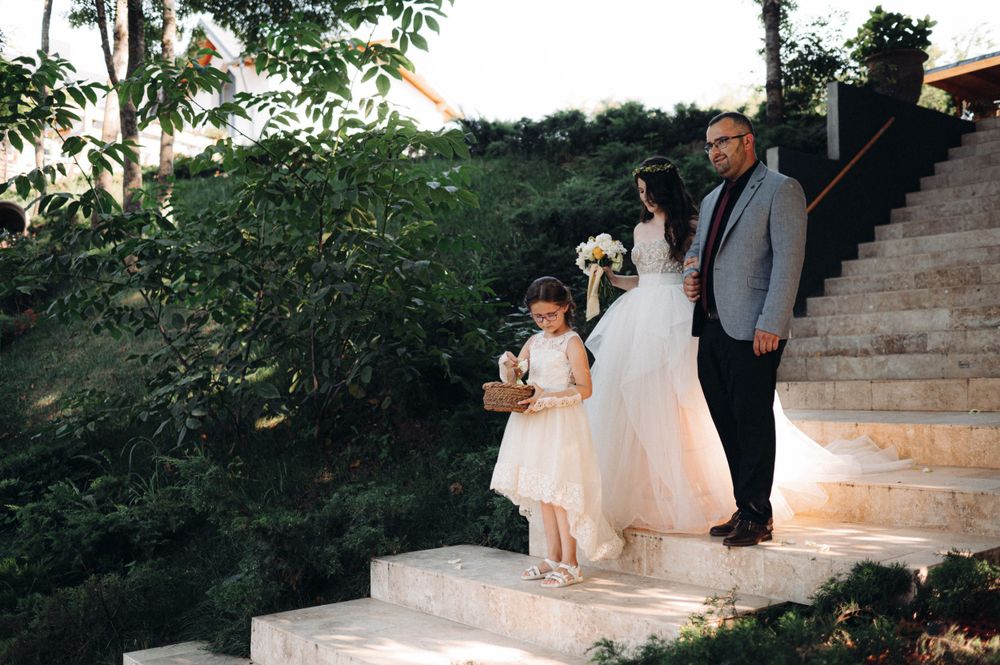 Wedding party members descending stone steps in formal attire.