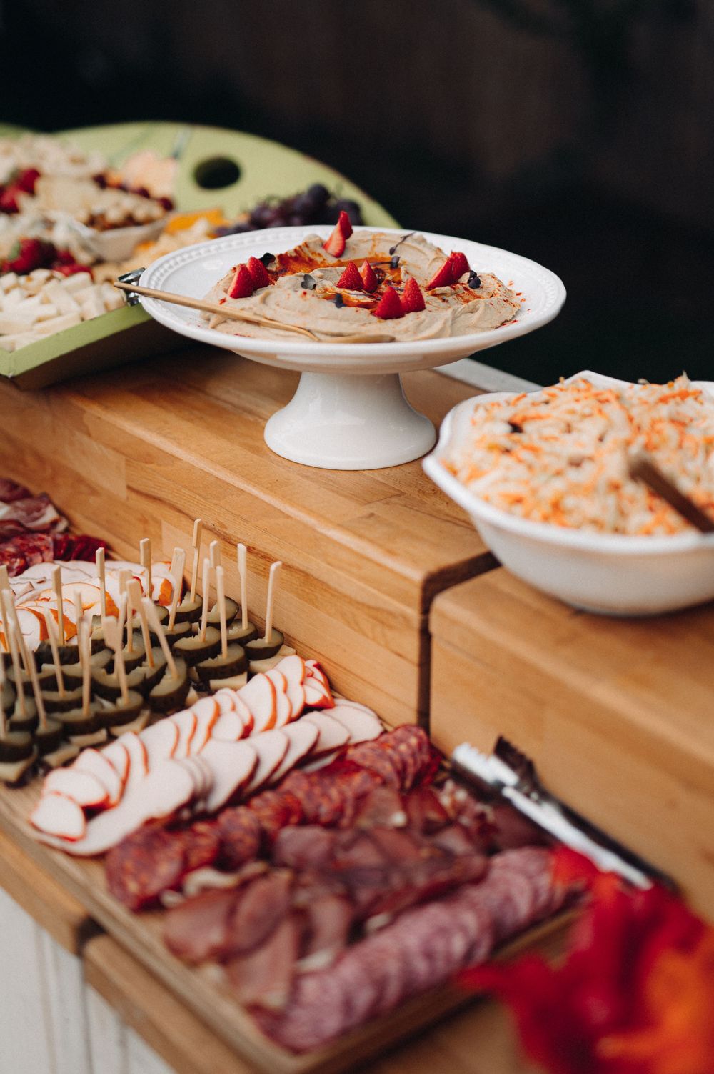 Elegant charcuterie and appetizer spread displayed on wooden table at catered event.