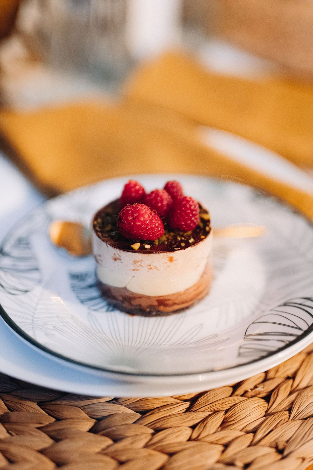 A dessert plate featuring a chocolate mousse topped with fresh raspberries on an ornate dish.