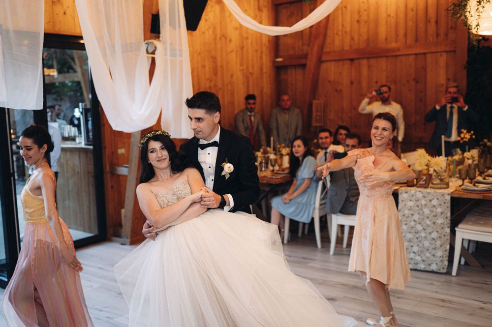Wedding celebration in rustic wooden venue with elegant white decorations and formal attire.