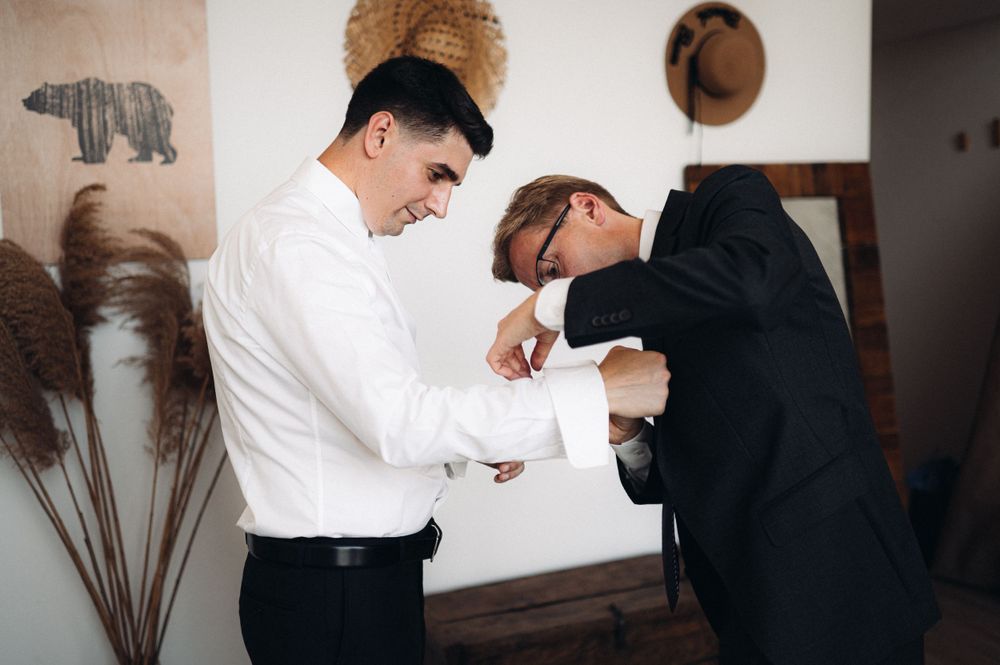 Two formally dressed people examining details in a minimalist room setting.