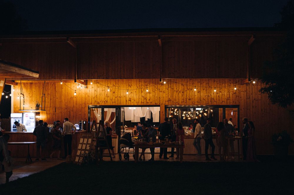 Illuminated wooden barn venue at night with guests gathered inside creating a warm, ambient atmosphere.