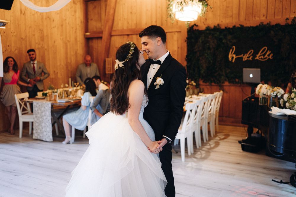 A romantic dance moment between newlyweds in a rustic wooden barn reception venue.