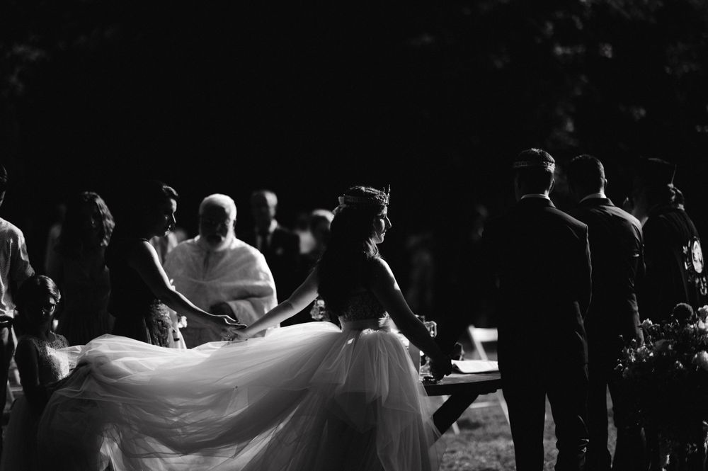 Black and white photo of wedding guests watching couple during outdoor reception.