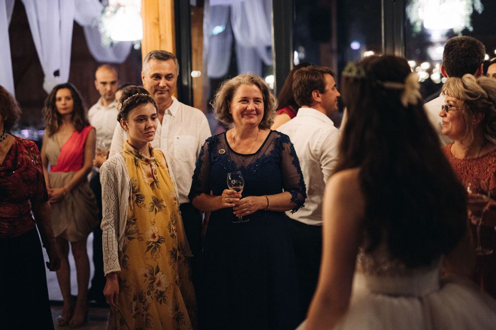 Wedding guests mingle and celebrate during an evening reception in a rustic venue.