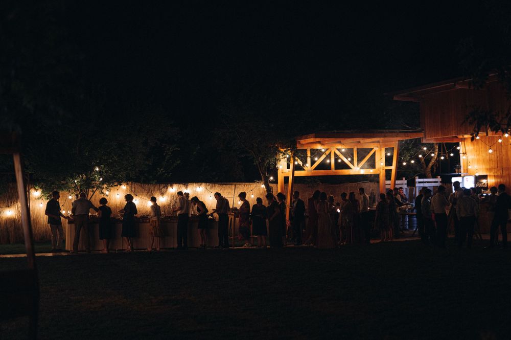 Nighttime outdoor venue with guests lined up under illuminated string lights.