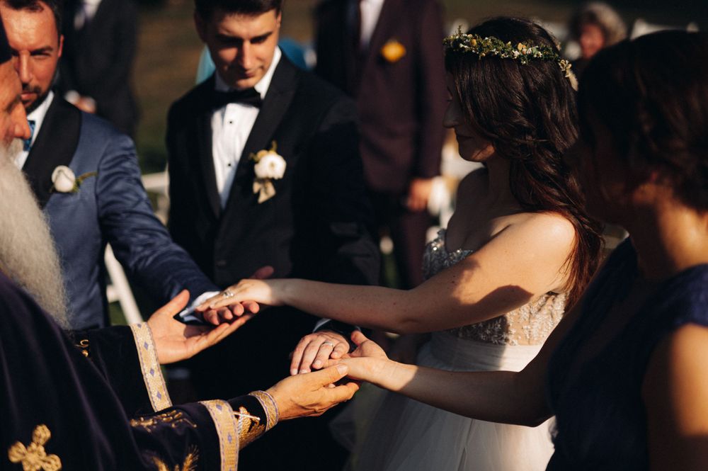 Wedding ceremony participants exchange rings during an outdoor service.