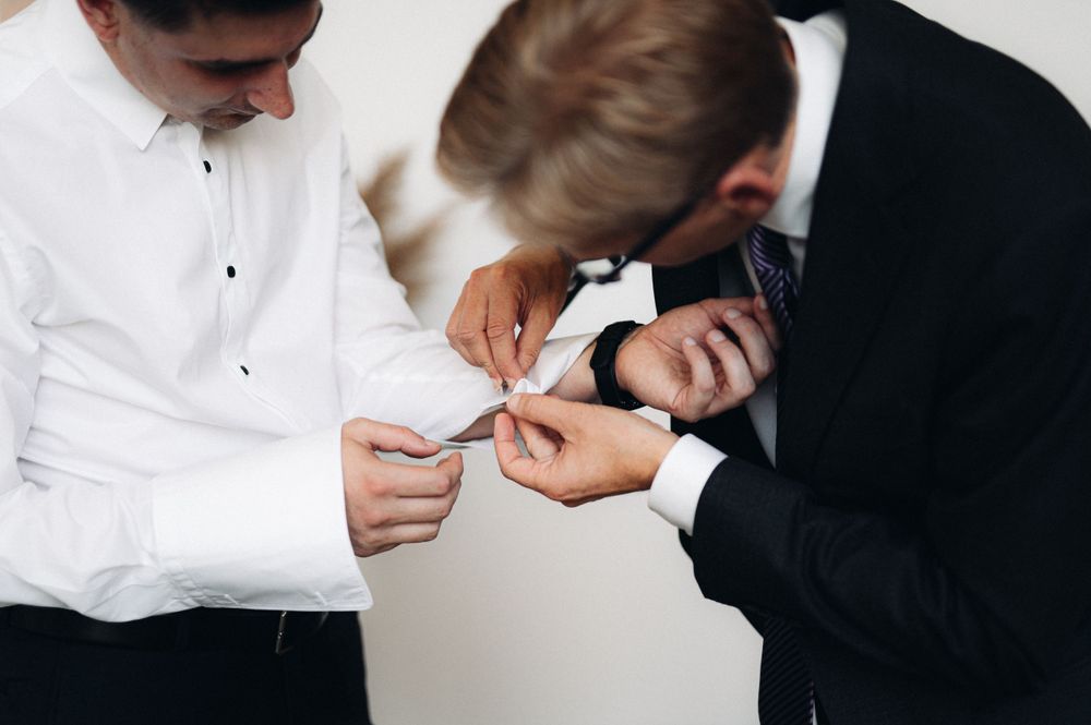 Close-up of formal-dressed people looking at small object together.