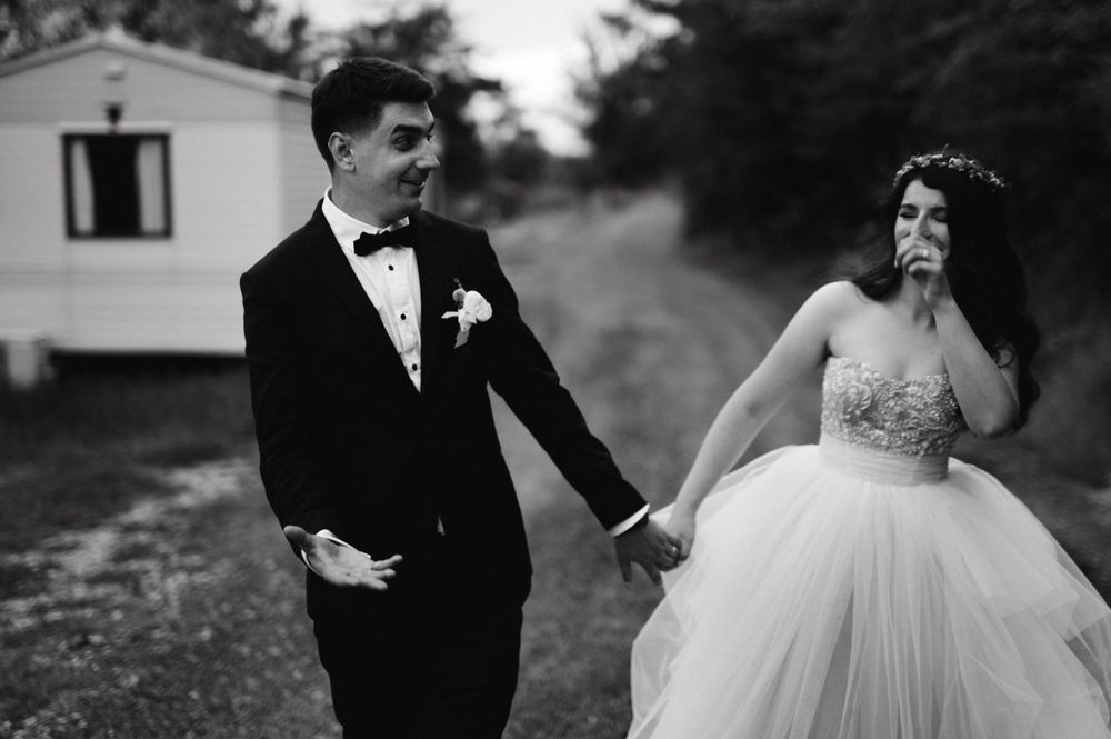 Black and white wedding photo capturing playful moment near mobile homes.