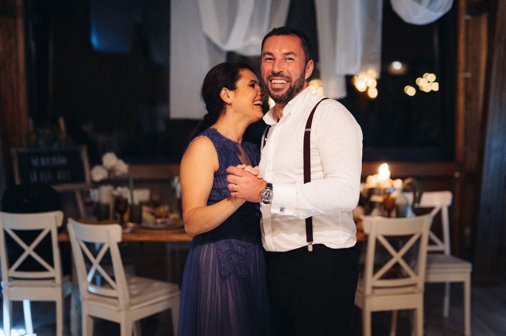 A couple shares a laugh while dancing at their evening wedding reception.
