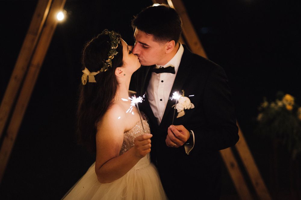 A couple shares an intimate moment under string lights at their wedding reception.