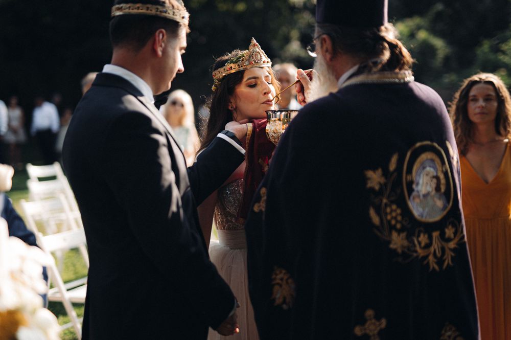 Intimate moment during a traditional wedding ceremony with ornate crowns and religious elements.