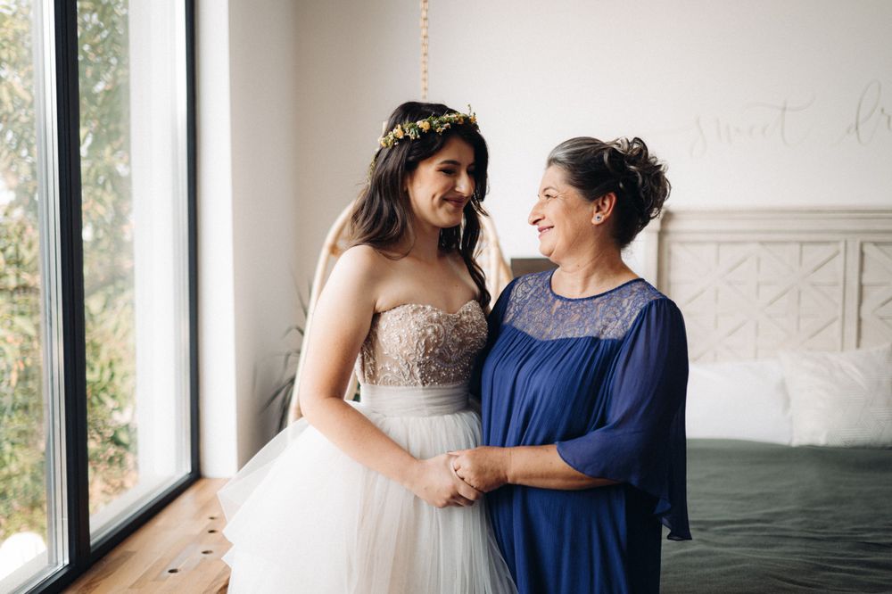 Sweet moment shared in a bright room featuring a stunning beaded wedding gown and navy blue dress.