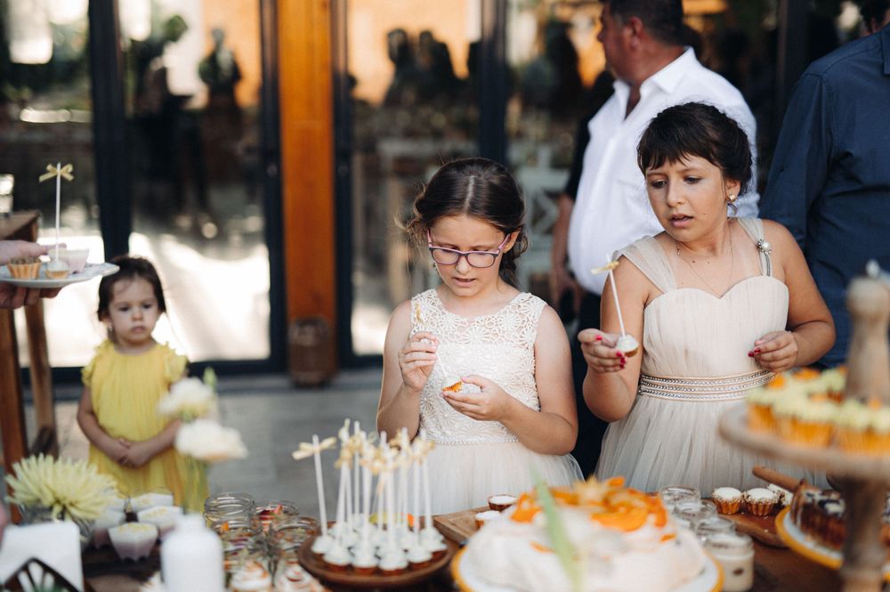 Wedding guests enjoying desserts and cake pops at an elegantly decorated dessert table.