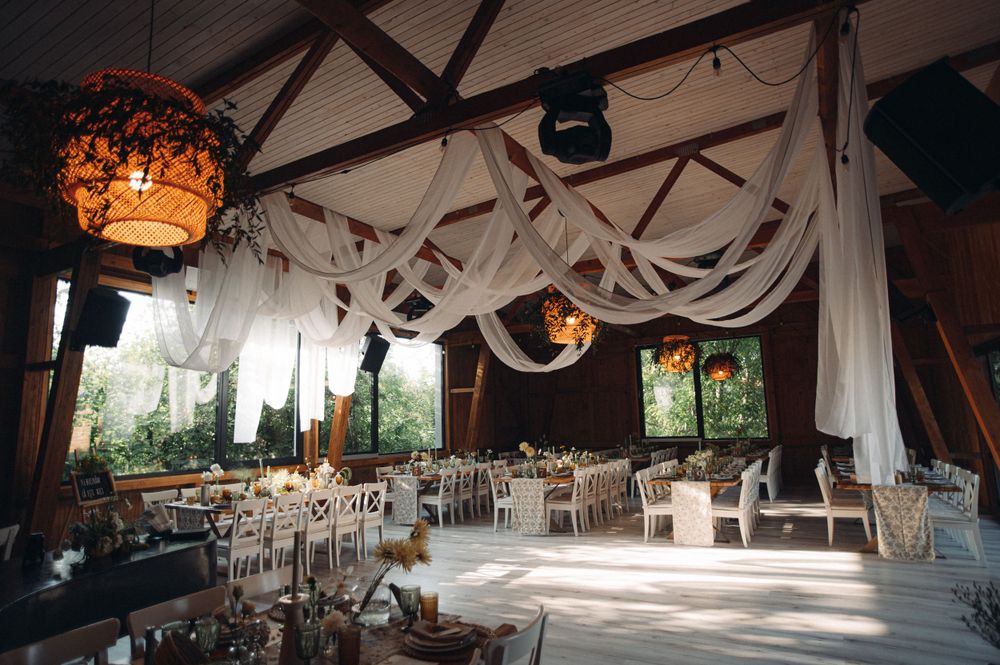 An elegant wedding venue decorated with flowing white fabric and warm lighting from hanging lanterns.